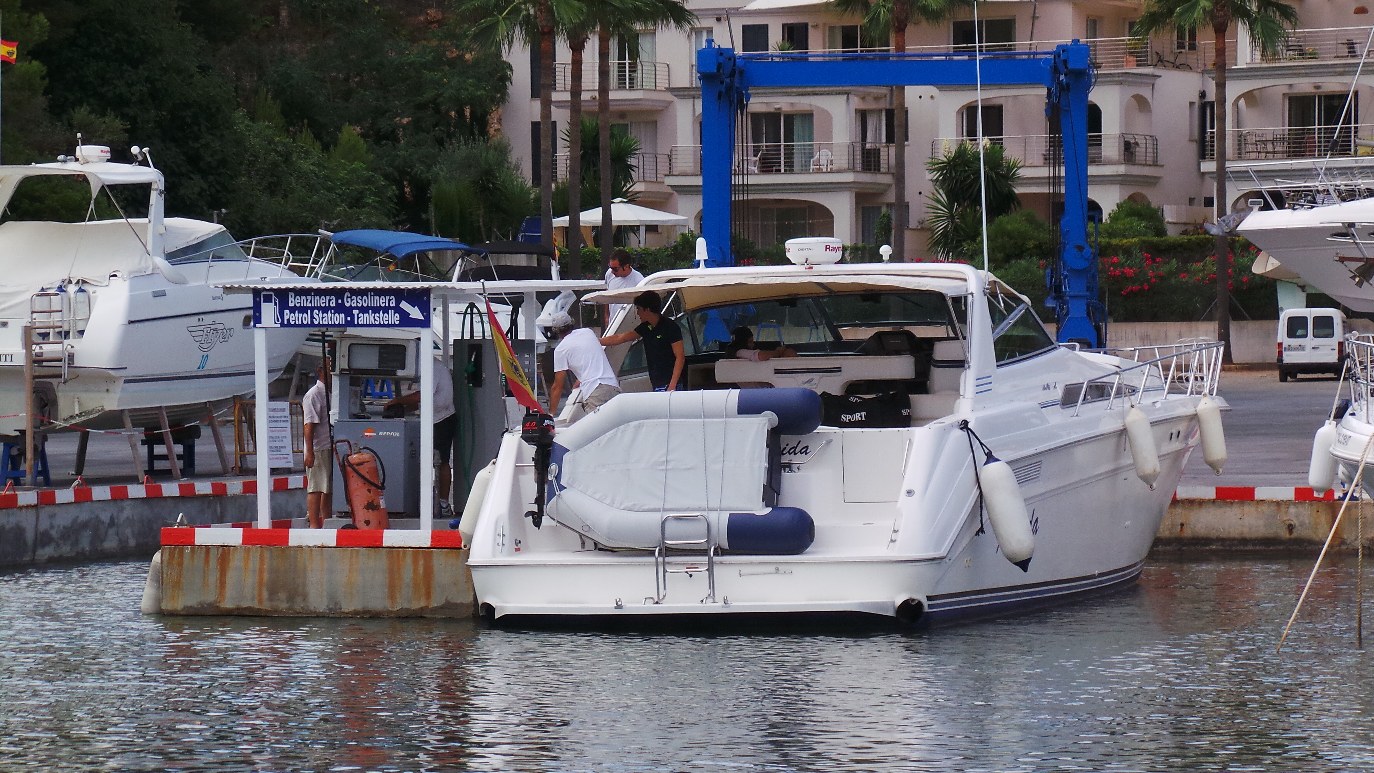 White motorboat beside a signed petrol pump at Porto Cristo marina.
