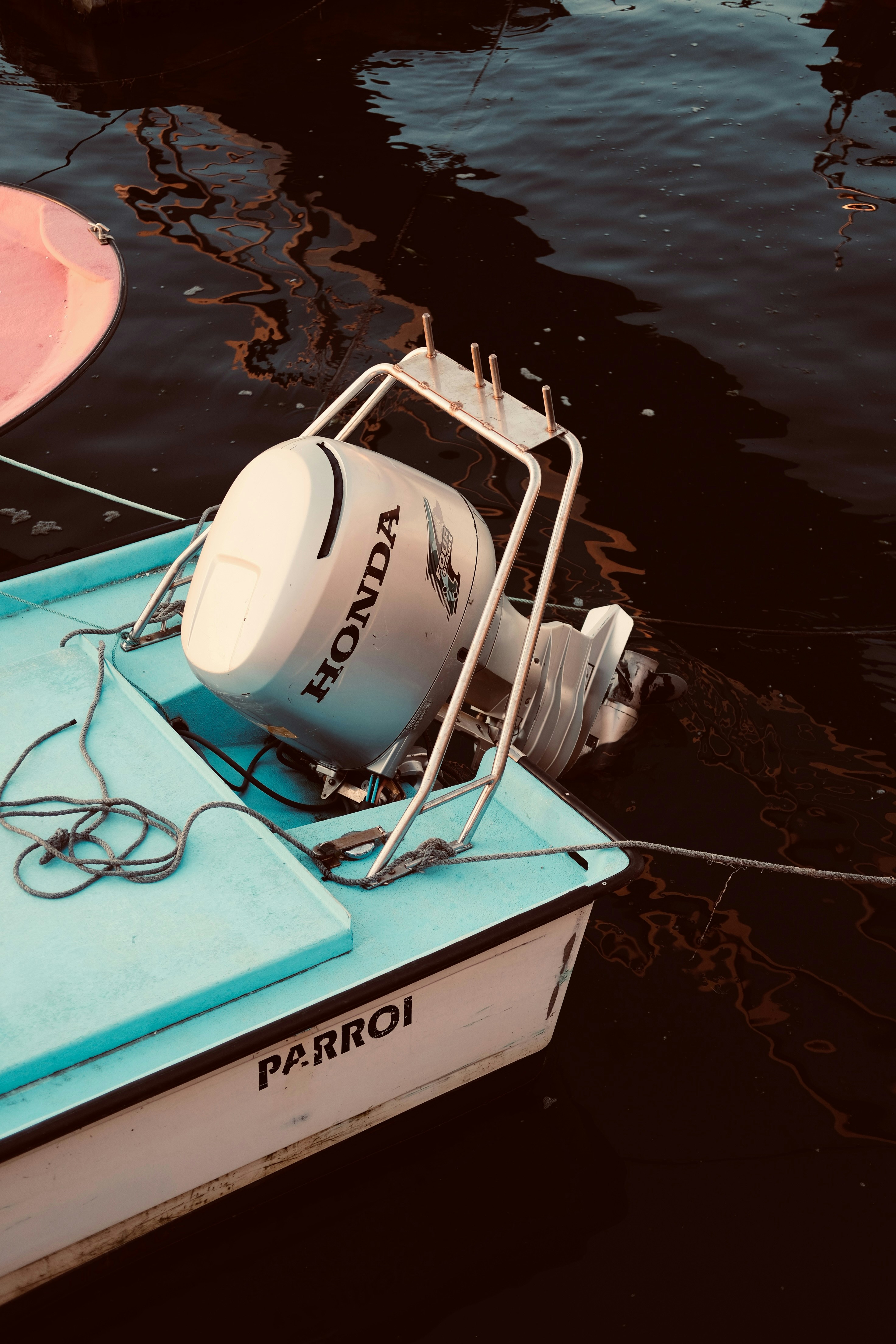 A white Honda outboard motor mounted at the stern of a small docked boat.